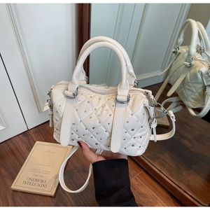 Detailed view of cream quilted handbag with rhinestone embellishments and silver hardware