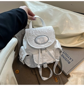 Détail du sac à dos blanc avec texture florale 3D et plaque métallique de marque