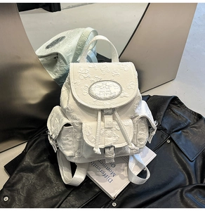 Gros plan du sac à dos en jacquard blanc à motif floral avec plaque logo argentée sur cuir