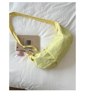 Detail einer hellgelben Nylon-Tasche in Knödelform mit verstellbarem Gurt und Herzanhänger