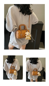 Detail einer braunen Boston-Tasche mit Bärenprint und einem Plüschbär-Anhänger-Zubehör
