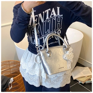Nahaufnahme der silbernen Handtasche mit Metallic-Effekt und Perlenherz-Anhänger