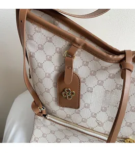 Detail of beige quilted tote bag featuring brown leather trim and gold clover charm