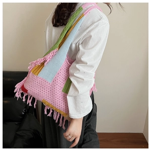 Detailed close-up of handmade knit tote bag featuring colorful tassels and texture