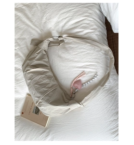Detail der cremefarbenen Nylon-Hobo-Tasche mit verstellbarem Gurt und Herzanhänger