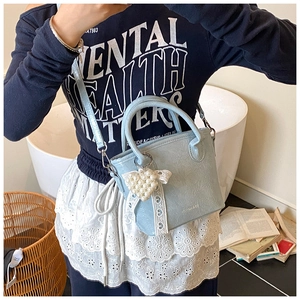 Detail der hellblauen Handtasche aus Faltenleder mit Perlenherz und Spitzenband-Deko