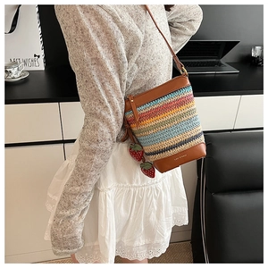 Detail of colorful woven bucket bag with strawberry charms and leather base logo