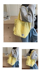 Detail view of yellow nylon tote bag with round coin purse and white text label