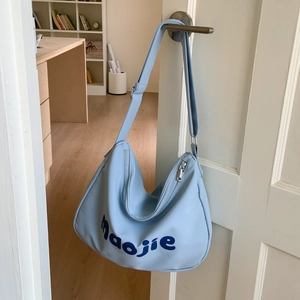 Detail of light blue canvas tote bag showing adjustable strap and Maojie letter print
