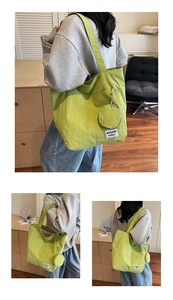Close-up of green nylon tote bag featuring a mini pouch and white woven brand logo label