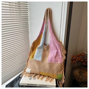Detail of bohemian knitted tote bag with colorful patchwork and fringe on a book