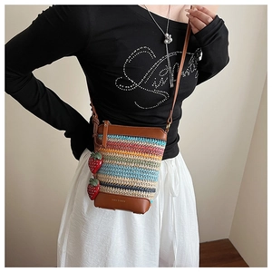 Détail du sac seau tissé arc-en-ciel avec base en cuir et breloques fraises