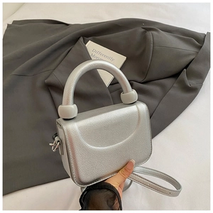Macro detail of silver metallic mini bag featuring unique grey resin bead handle accents