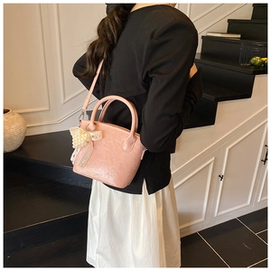 Nahaufnahme der rosa Handtasche aus Faltenleder mit Perlenanhänger und Modeprägung