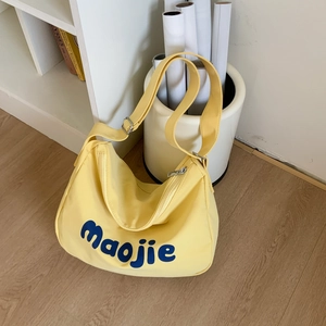 Detail of yellow canvas shoulder bag with blue Maojie lettering and adjustable strap