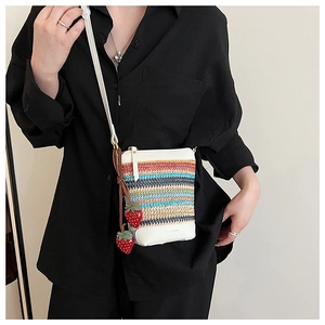 Détail du sac bandoulière en paille tissée colorée avec cuir blanc et breloques fraises