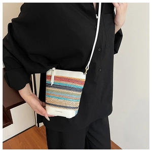 Detail of colorful woven crossbody bag featuring stripe patterns and a white leather base