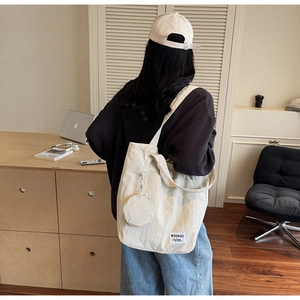 Detail view of off-white nylon tote bag with small zip pouch shown on model