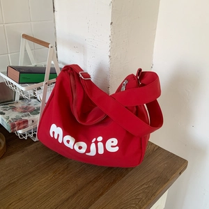 Detail of red canvas tote bag with white lettering on dark wood background