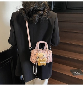 Rosa Boston-Tasche mit Cartoon-Bären-Druck und Plüsch-Anhänger an einem Model