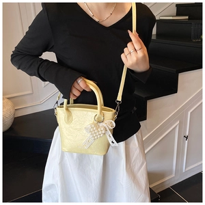 Détail du sac plissé jaune avec pendentif perle papillon et bandoulière amovible