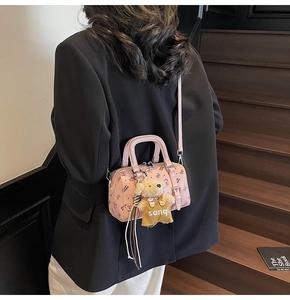 Rosa Boston Bag mit Bärendruck und Plüsch-Anhänger auf einer dunklen Treppe
