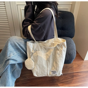Close-up of beige waterproof nylon tote bag with side pocket and round mini coin purse detail