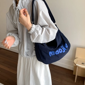 Model wearing a navy blue crescent canvas tote bag with artistic maojie text detail