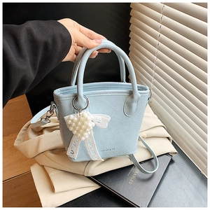 Gros plan d'un sac seau bleu clair plissé avec breloque cœur perle et ruban de dentelle