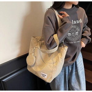 Detail of waterproof nylon tote bag with small round coin purse and branded woven label