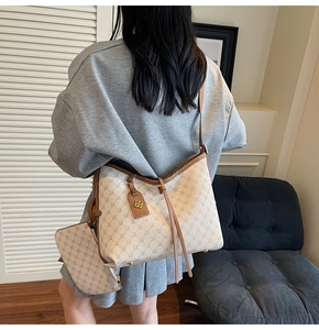 Detailed view of monogram tote bag with tassel charm and small pouch on shoulder