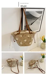 Detail of straw tote bag showing daisy embroidery and brown leather handles