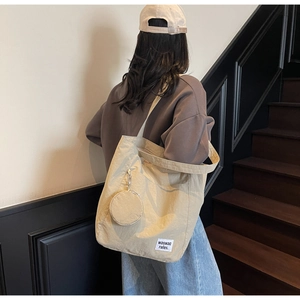 Detail of beige nylon tote bag featuring a matching mini round coin purse and logo patch