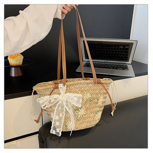 Detail of hand-woven straw tote bag with white daisy embroidery and lace bow decoration