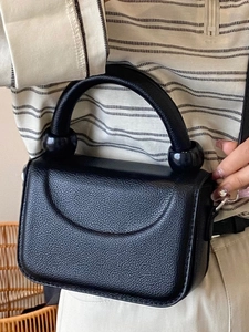 Chic black litchi pattern leather handbag with unique spherical decorative handle accents
