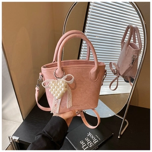 Vue détaillée du sac seau plissé rose avec breloque cœur en perles et poignée en métal