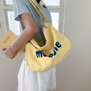 Detail of yellow canvas crescent tote bag featuring artistic blue text print