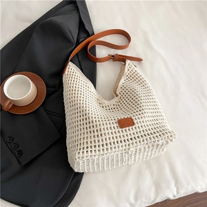 Macro detail of creamy hollow woven tote bag with premium brown leather strap and logo
