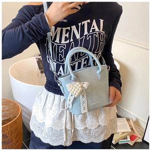 Dettaglio della borsa in pelle PU azzurra con ciondolo a cuore di perle e fiocco in pizzo