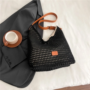 Detail of black woven tote bag featuring brown leather strap and adjustable metal buckle