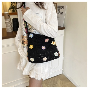 Detail einer schwarzen Häkel-Tote-Bag mit bunten floralen Strickmustern und Trageriemen