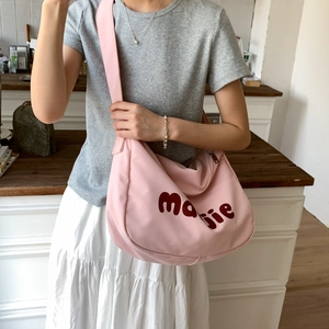 Detailed view of pink canvas hobo bag with artistic mojjie text on shoulder strap