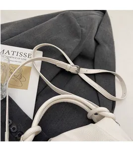 Detail showing white litchi grain leather texture and adjustable strap on a cloud bag