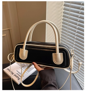 Detail of a black and white contrast cylindrical shoulder bag with adjustable strap