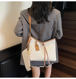 Detail view of stylish monogram tote bag with adjustable shoulder strap and metal charm