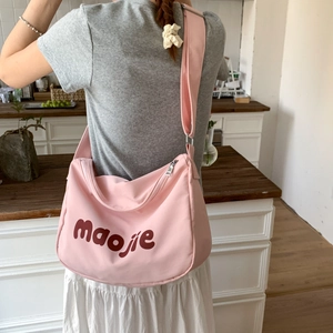 Pink canvas crossbody tote bag with wide adjustable strap and large letter print detail