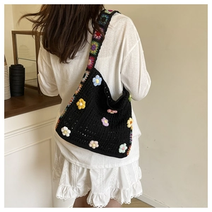 Detail einer schwarzen Häkeltasche mit bunten 3D-Blumen und Regenbogen-Schultergurt