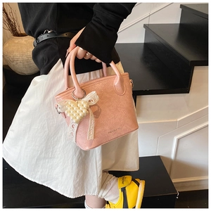 Dettaglio della borsa rosa in pelle PU con ciondolo a fiocco di perle e logo inciso