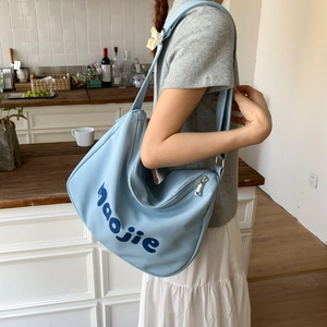 Detail of light blue hobo canvas bag with maojie lettering worn by a model