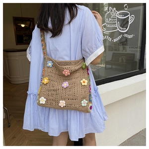 Detail einer großen braunen Häkeltasche mit bunten 3D-Strickblumen im modischen Streetstyle